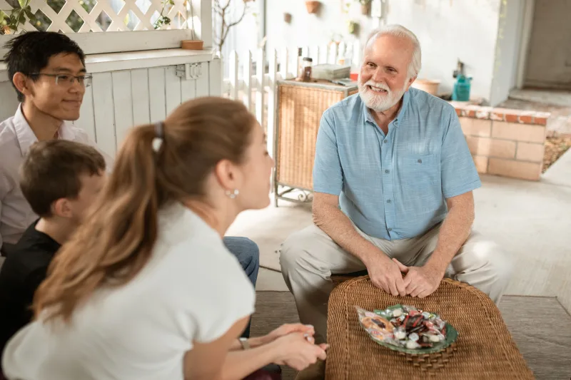 Older man smiling during a family conversation on a patio