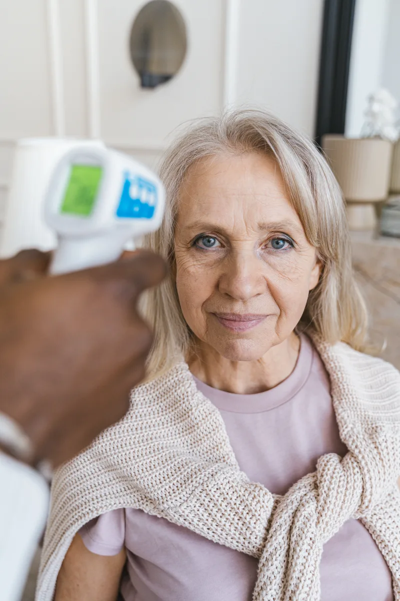 Older woman having her temperature checked with a digital thermometer